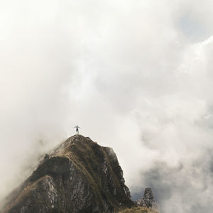 Distant view of man jumping over mountain in foggy weather