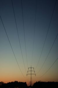 Low angle view of electricity pylon against sky at sunset