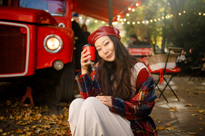 Beautiful asian woman in plaid coat and red leather hat on street with coffee