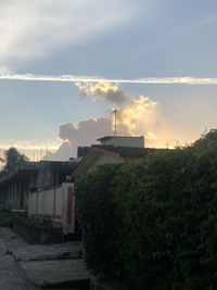 Houses by street against sky during sunset