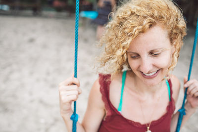 Close-up of smiling woman sitting on swing outdoors