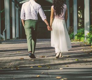 Rear view of couple walking hand in hand