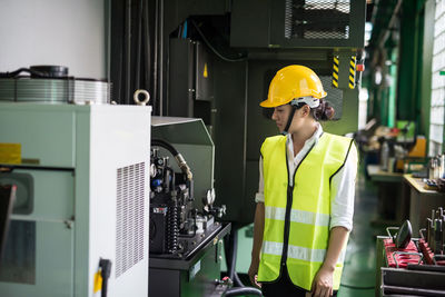 Waist up female worker walk in factory to check electronic machine and steel equipment.