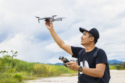 Man holding drone while standing against sky