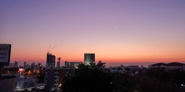 Illuminated buildings against sky during sunset