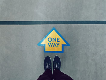 Low section of person standing on road sign