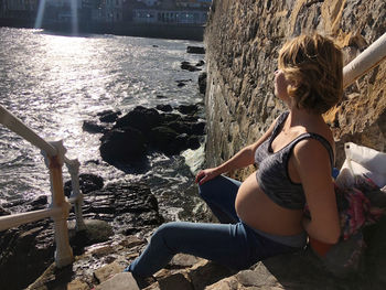Rear view of woman sitting on rock