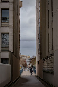 People walking on road amidst buildings in city against sky