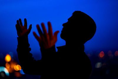 Portrait of silhouette woman against illuminated blue sky