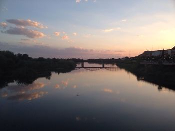 Bridge with reflection over tagus river against sky during sunset