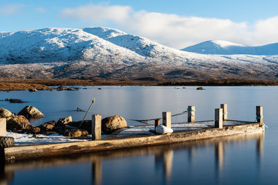 Scenic view of lake by snowcapped mountains against sky