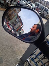 Reflection of man photographing car on side-view mirror
