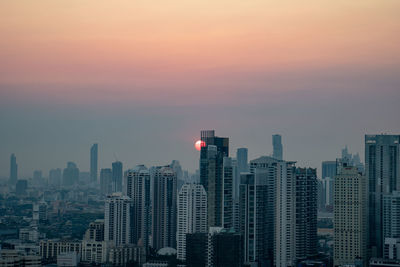 Modern buildings in city against sky during sunset