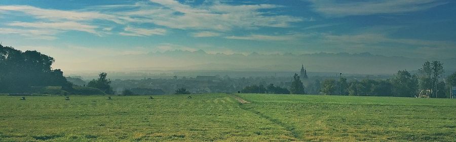Scenic view of grassy landscape against cloudy sky