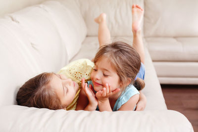 Happy kids lying on sofa at home