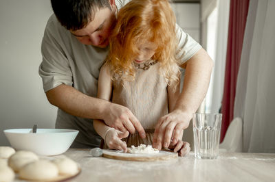 Father teaching daughter to prepare cheesecake at home