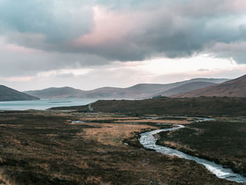 Moody and scenic view of mountains against sky and sea