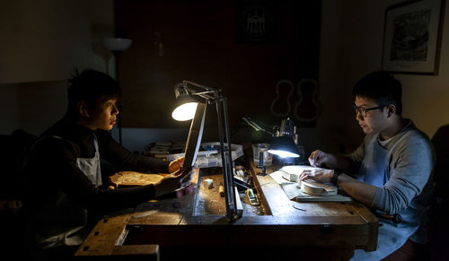 Pair of craftsmen violin maker while working on a new violin in the workshop