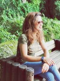 Young woman looking away while sitting on bench
