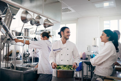 Male and female chefs communicating while preparing food in commercial kitchen