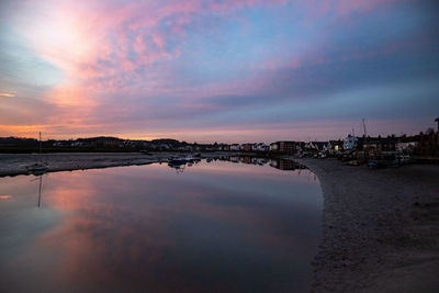 Scenic view of sea by buildings against sky during sunset