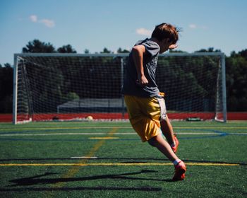 Rear view of boy playing on soccer field