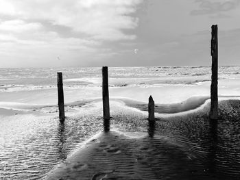 Wooden posts on beach against sky