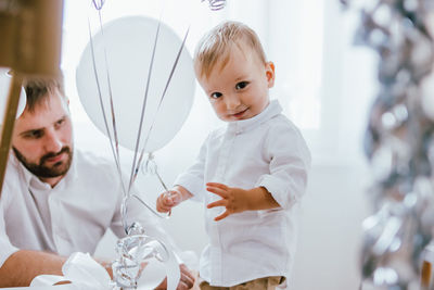 Portrait of son against father in background at home