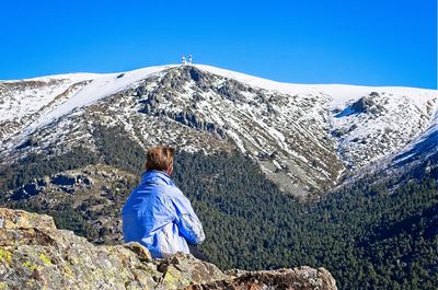 Rear view of woman in front of mountain against clear blue sky