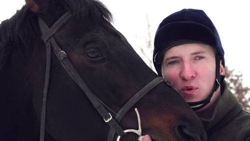 Close-up, portrait of a male rider and the face of a beautiful black horse. snowy winter day.