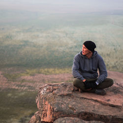 Young man sitting on rock