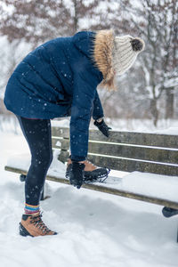 Full length of woman wearing shoe on bench during winter