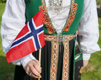 Midsection of woman wearing traditional clothing while holding norwegian flag