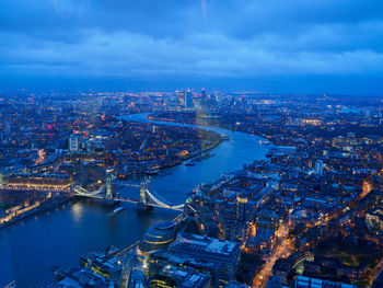 High angle view of illuminated buildings by river against sky