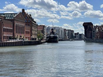 Buildings by river against cloudy sky