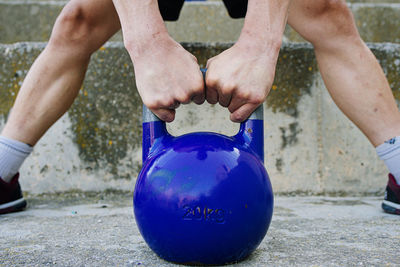 Man lifting a kettelbell crossfit weight in an urban enviroment.