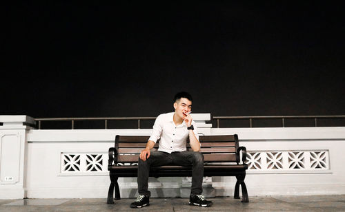 Young man looking away while sitting on bench