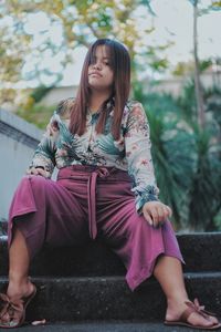 Woman looking away while sitting on bench