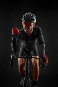 Portrait of man riding bicycle against black background
