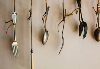 Close-up of old eating utensils hanging against wall