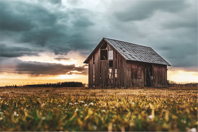 Barn on field against sky during sunset