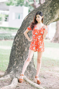 Full length of young woman standing on tree trunk