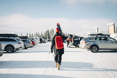 Rear view of woman walking at parking lot during winter