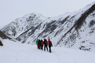 Rear view of people walking on snowcapped mountain