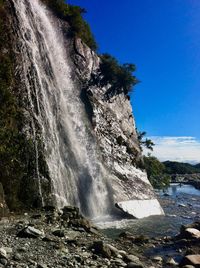 Scenic view of waterfall against sky