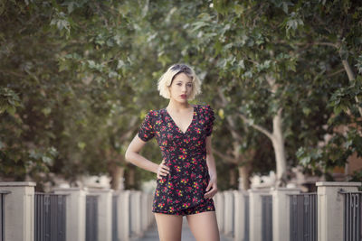 Portrait of young woman standing against trees