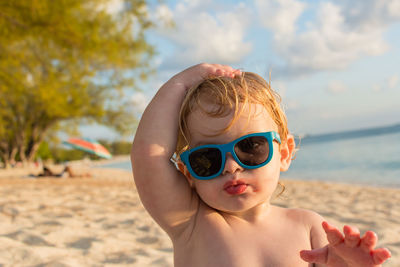 Portrait of shirtless boy wearing sunglasses at beach
