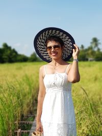 Woman wearing hat while standing on field against sky