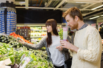 Young couple selecting vegetables at supermarket