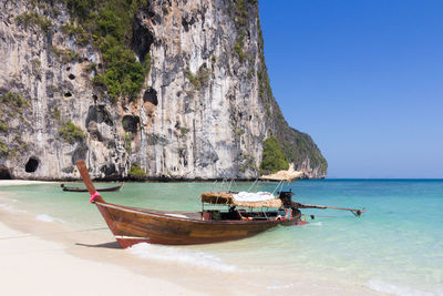 Boat moored on sea shore against clear sky